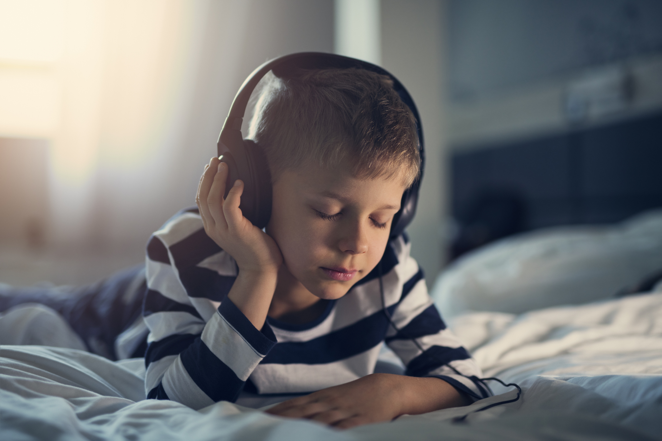 Boy listening to podcasts in bed